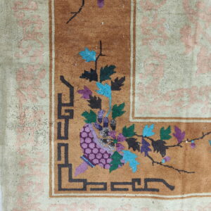 Rust field rug corner with purple and teal florals, geometric black trim, and a pale pink scrolled border.
