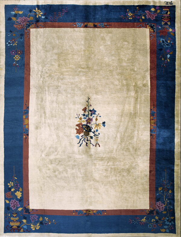 Cream rug with a single central floral motif, surrounded by rust and deep blue borders with complex floral patterns.