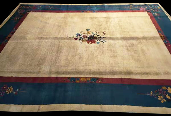 Cream rug featuring a central floral motif and wide teal and maroon decorative borders.