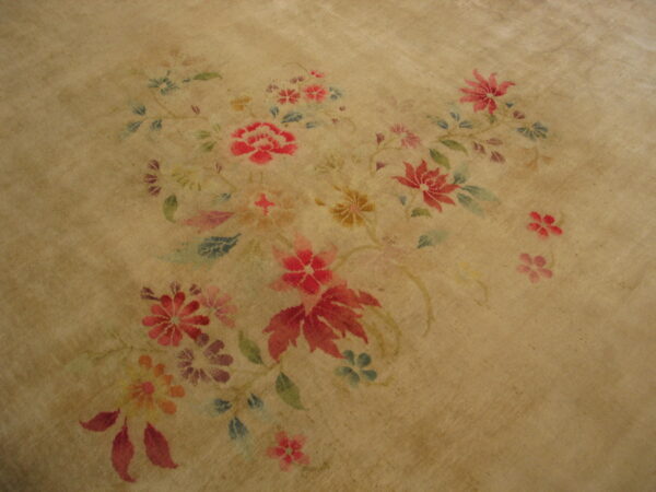Muted tan rug surface detailed with a central arrangement of red, pink, blue, and green floral motifs.