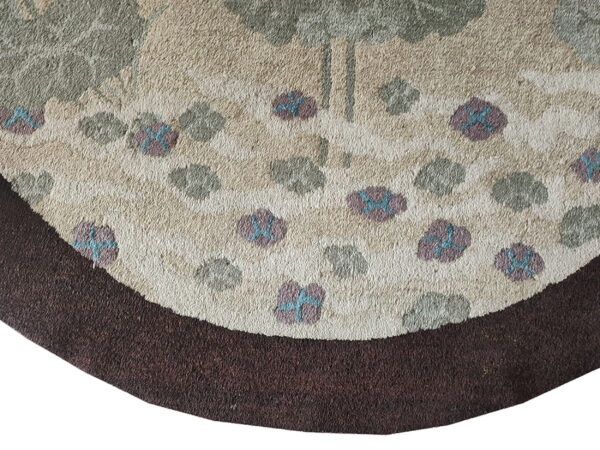 Close-up of a rounded rug section with textured cream pile, a dark brown border, and scattered floral elements.
