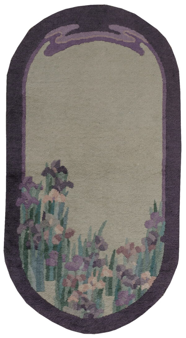 Oblong rug with a deep purple frame, sage green field, and a colorful floral iris pattern.