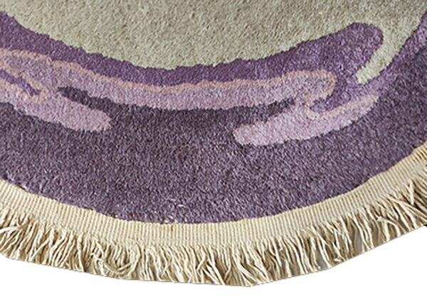 Textured round rug edge showing curved bands of beige and purple pile with a cream woven fringe.