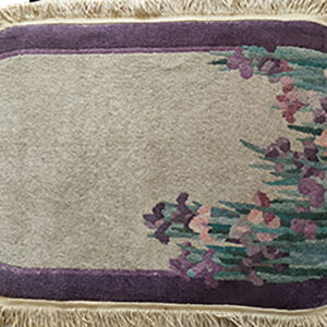 Oblong rug with a beige field, a purple border, cream fringe, and floral purple and green motifs.