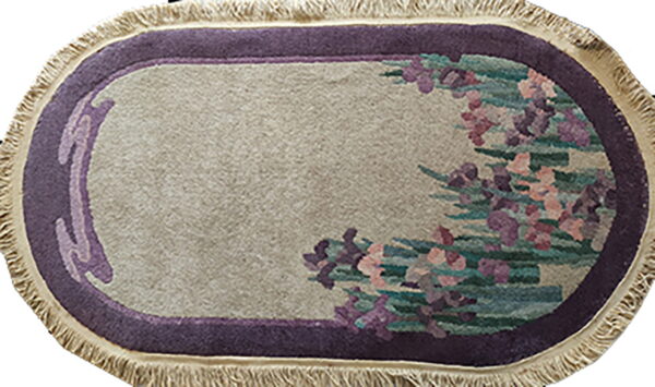 Oblong rug with a beige field, a purple border, cream fringe, and floral purple and green motifs.