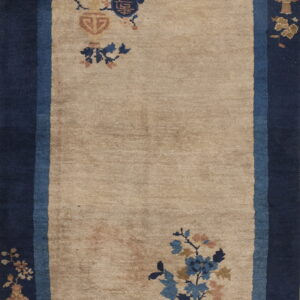 Rectangular tan rug featuring a wide navy border, a light blue guard border, and scattered floral designs.