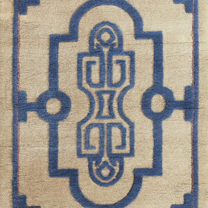 This textured rug displays a detailed blue interlocking geometric design against a tan background.