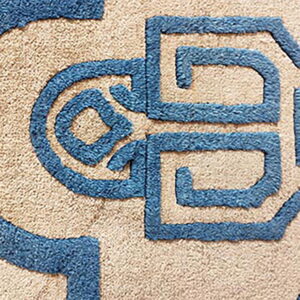 A plush, shaggy rug features blue carved geometric shapes contrasting against a tan background.