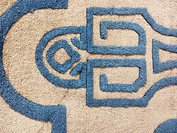 A plush, shaggy rug features blue carved geometric shapes contrasting against a tan background.