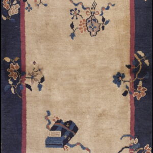 Low-pile rug with a tan center field, magenta guard border, and wide navy blue decorative main border.