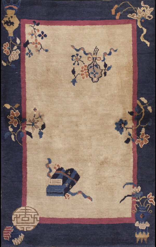 Low-pile rug with a tan center field, magenta guard border, and wide navy blue decorative main border.