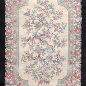 Light beige rug with a central field of pink and blue blossoms and a wide, intricate floral border.