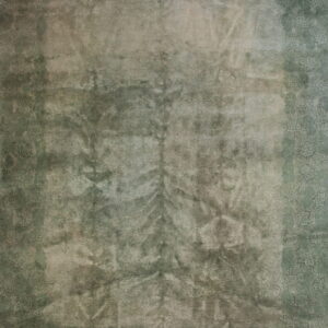 Distressed green rug with a faded floral border surrounding a lighter central field of subtle pattern.