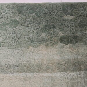 Textured green rug with carved floral pattern and an ombre effect fading into light beige.