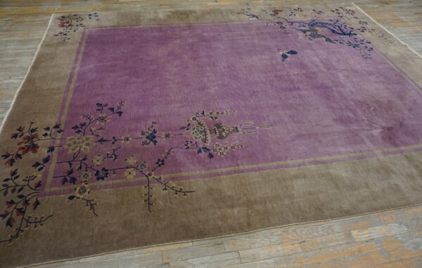 Purple rug with a wide taupe border and decorative corner floral motifs on distressed grey wood flooring.
