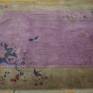 Low-pile purple rug with olive border and floral pattern lies centered on rustic wooden planks.