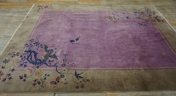 Low-pile purple rug with olive border and floral pattern lies centered on rustic wooden planks.