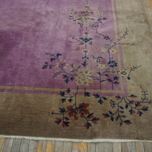 Section of a purple rug with brown border and complex floral design on rustic wood planks.