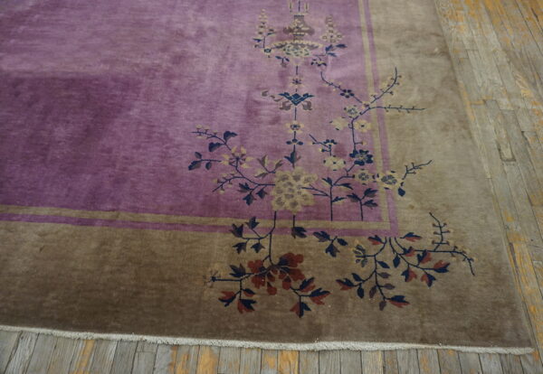 Section of a purple rug with brown border and complex floral design on rustic wood planks.