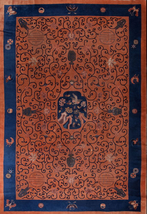 Rust and navy rug with a dense scrolling vine pattern, symbolic motifs, and a detailed central panel.