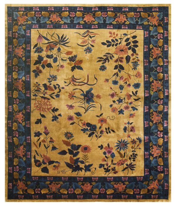 A gold, high-pile rug with blue, rust, and pink sprawling florals inside a dense navy botanical border.