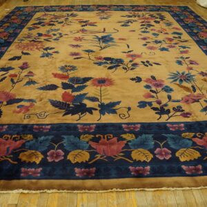Gold rug with a plush pile, colorful scattered flowers, and a detailed navy blue floral border on wood.