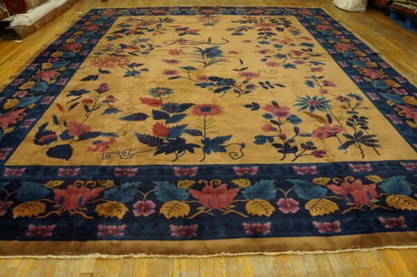 Gold rug with a plush pile, colorful scattered flowers, and a detailed navy blue floral border on wood.