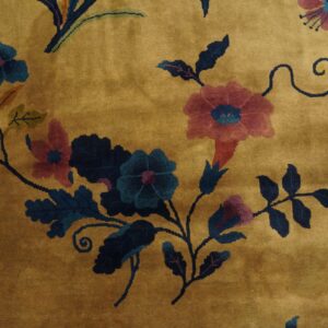 Mustard yellow high-pile rug with dark teal, pink, and purple floral and vine patterns.