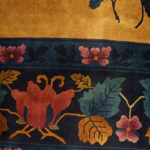 Golden yellow rug with a dark border patterned with large red, teal, and orange flowers.