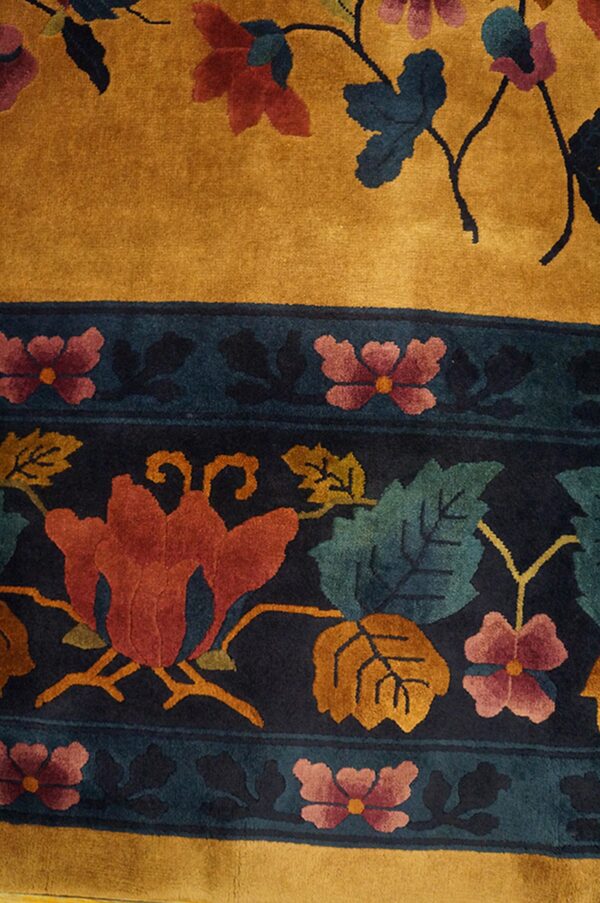 Golden yellow rug with a dark border patterned with large red, teal, and orange flowers.