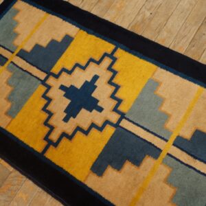 Stepped geometric runner rug featuring dark blue, yellow, tan, and light blue on plank wood flooring.
