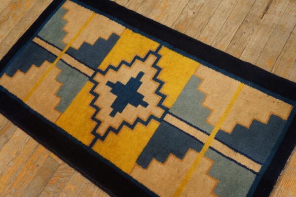 Stepped geometric runner rug featuring dark blue, yellow, tan, and light blue on plank wood flooring.