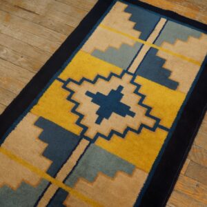 Stepped geometric runner rug in yellow, navy, beige, and blue on distressed wooden planks.