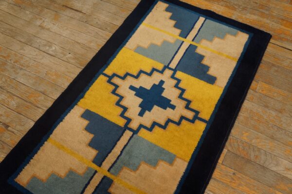 Stepped geometric runner rug in yellow, navy, beige, and blue on distressed wooden planks.