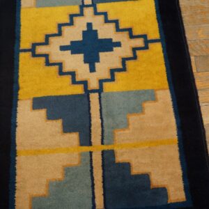 Yellow, navy, and tan geometric runner rug showing stepped designs on distressed hardwood floors.