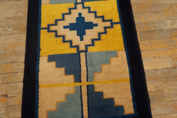 Yellow, navy, and tan geometric runner rug showing stepped designs on distressed hardwood floors.