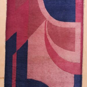 Abstract low-pile rug featuring bold geometric shapes in navy blue, magenta, and blush pink on a wood floor.