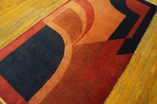 Curved and geometric shapes in navy, terracotta, and red on a short-pile rug over yellow wood planks.