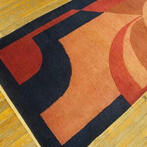 Navy, rust, and red geometric rug with curved shapes covers bright yellow plank hardwood flooring.