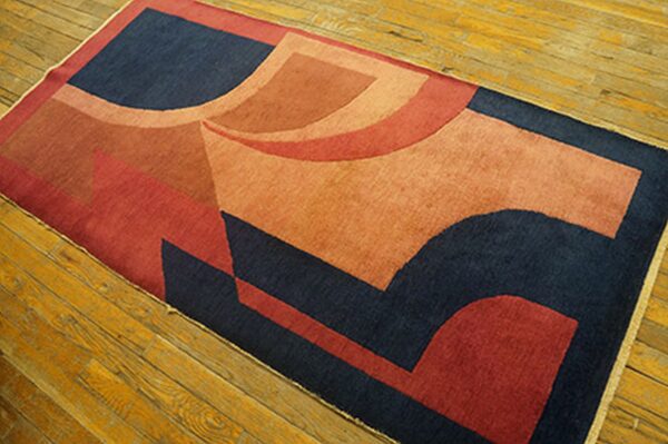 A runner rug with dark blue, rust, and orange abstract geometric shapes lies on wooden floorboards.