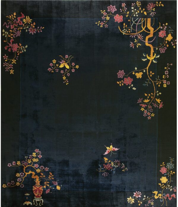 A velvety dark blue rug featuring stylized gold and pink floral branches in the corners.