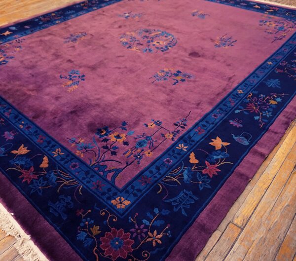 Velvety purple rug with multicolored scattered floral motifs and a wide dark blue patterned border on wood floor.