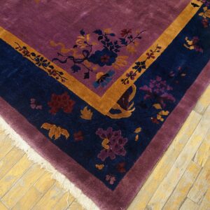 Purple high-pile rug corner with a navy blue and gold floral border on rustic wood floors.