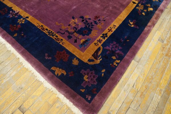 Purple high-pile rug corner with a navy blue and gold floral border on rustic wood floors.