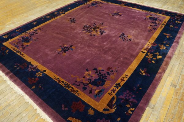 Deep purple rug with wide navy and gold floral borders on light yellow wooden flooring.