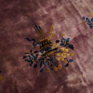 Deep purple pile rug featuring blue and gold ornamental vase and scattered floral vine patterns.