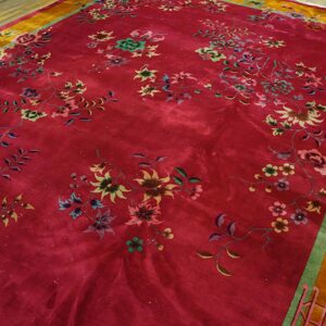 Deep magenta rug with high sheen, green and pink floral pattern, and a wide gold border on wood floor.