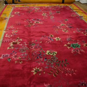 Deep magenta rug with multicolored floral motifs and a wide gold yellow decorative border.