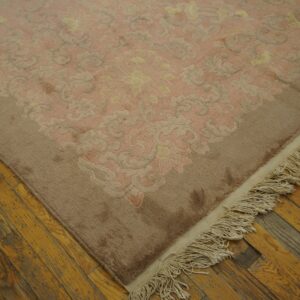 High-pile pink and tan rug with a carved floral pattern rests on rustic yellow wood planks.