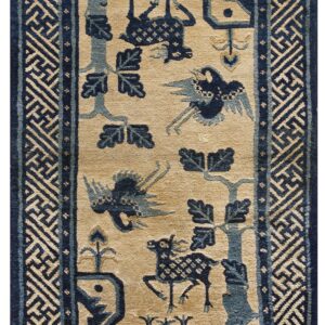 Tan rug with navy and muted blue stylized animals and foliage, framed by a wide fretwork border.